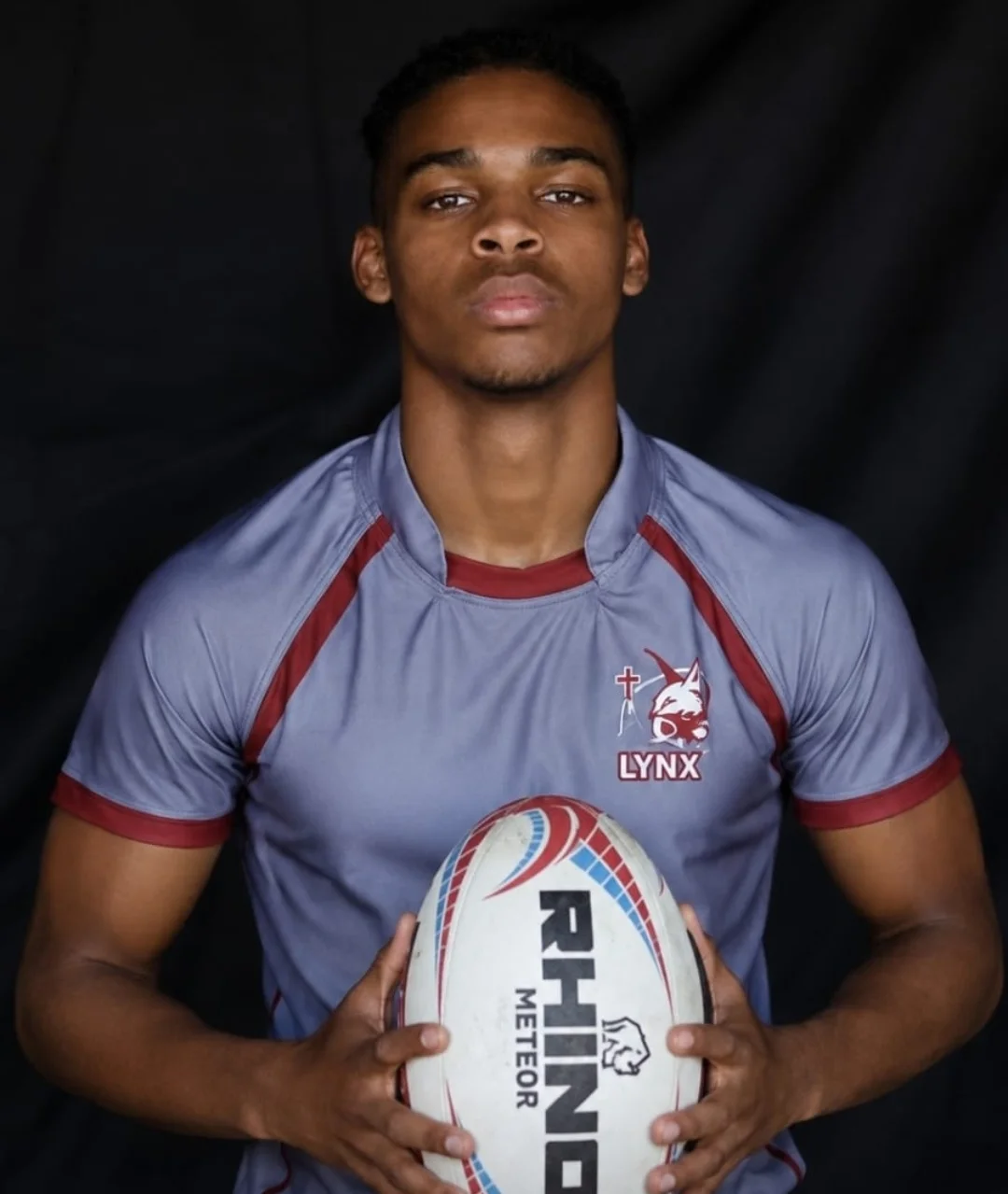 Faith holding a rugby ball in his Lynx rugby kit